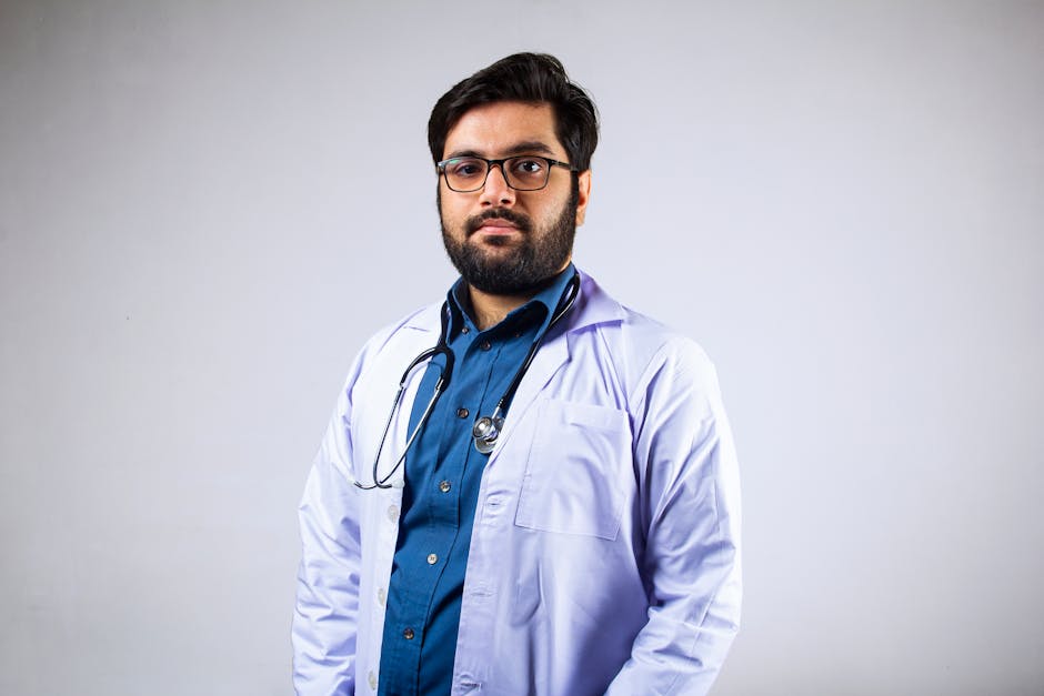Portrait of a bearded male doctor in a white coat with a stethoscope in a studio setting.